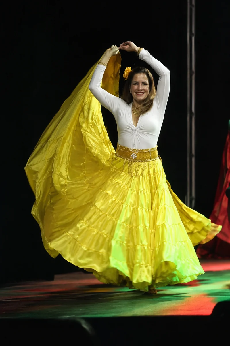 Sarita Del Sol dançando dança cigana, com saia amarela rodada, em um palco