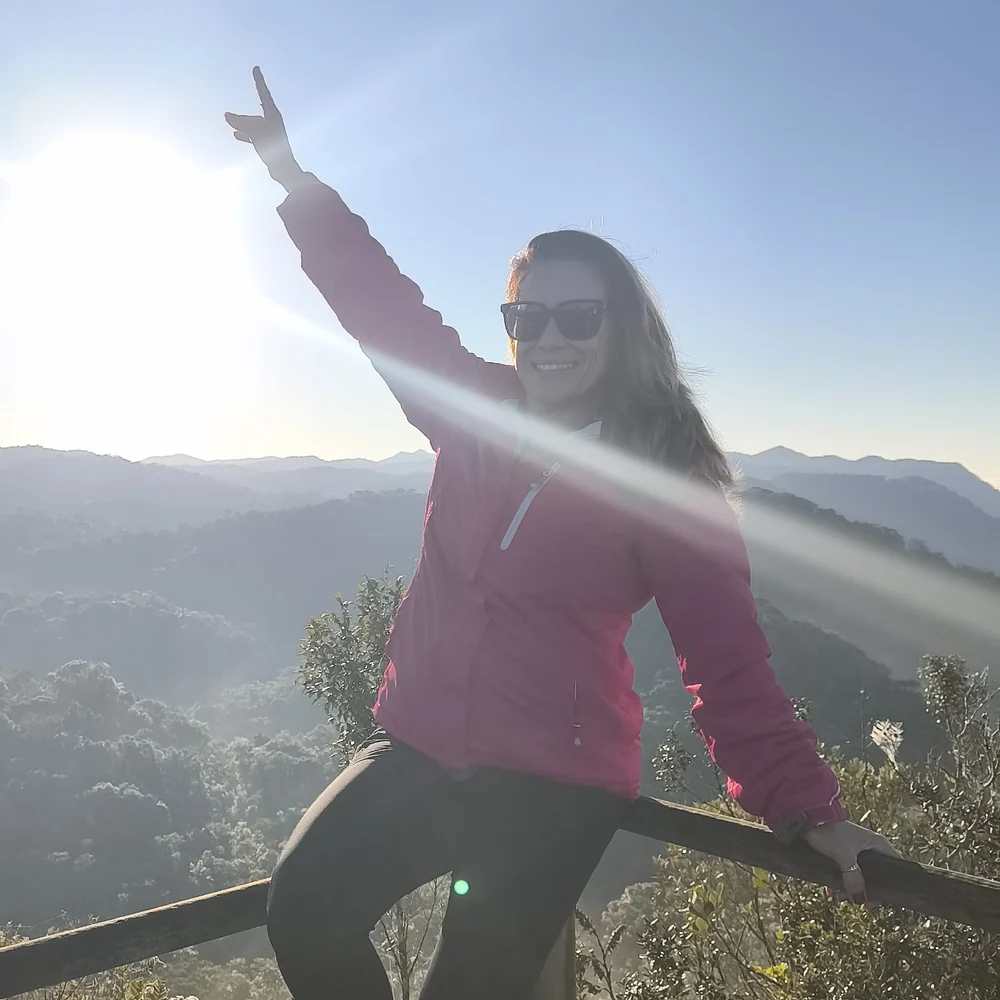 Sarita Del Sol em uma trilha ao nascer do sol, com os braços para o alto